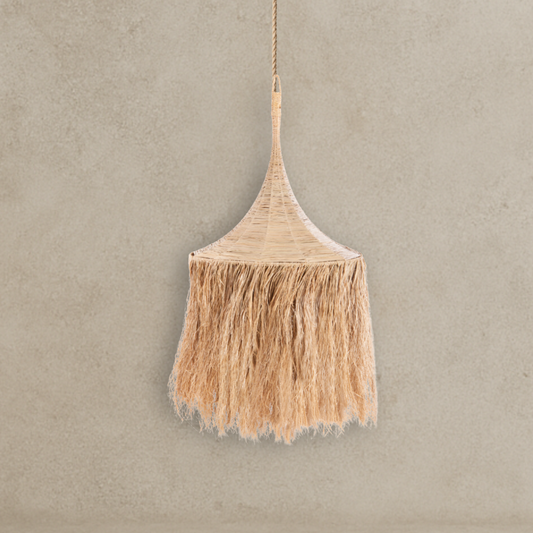 Woven broom with tassels hanging against a beige wall