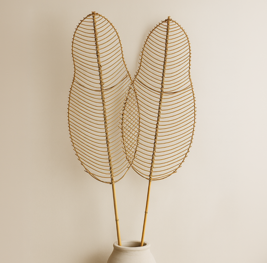 Decorative wire leaf sculpture in a white vase against a beige background