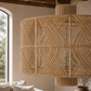 Woven natural fiber pendant light hanging in a room with a window and decor.