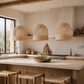 Kitchen with wicker pendant lights, wooden stools, and a neutral color palette.