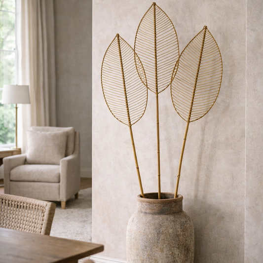 Decorative vase with leaf-like stems against a neutral wall in a room with furniture.