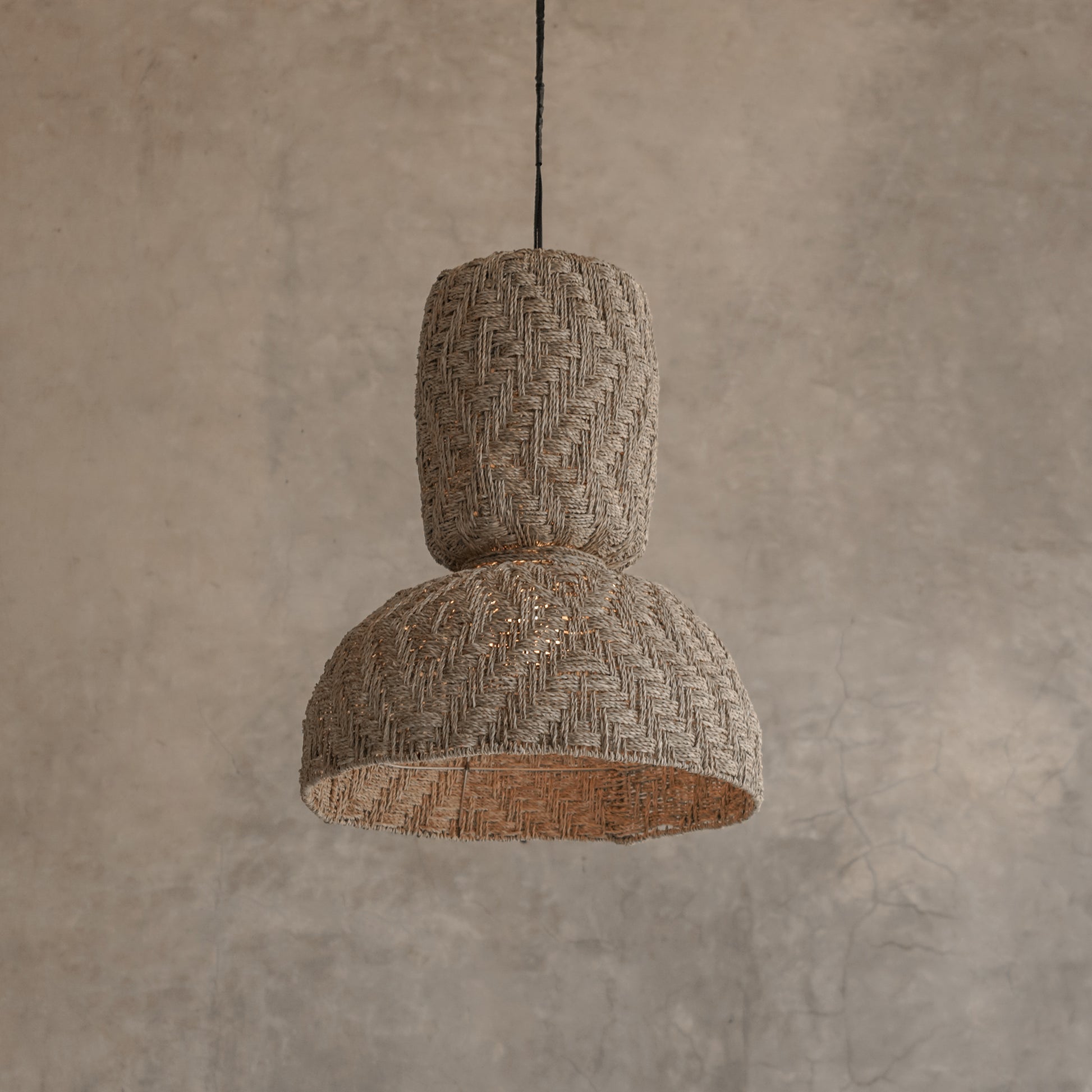 Textured pendant light hanging against a beige wall