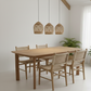 Dining area with wooden table and chairs under wicker pendant lights.