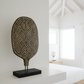 Decorative sculpture with geometric patterns on a white surface in a minimalistic room.