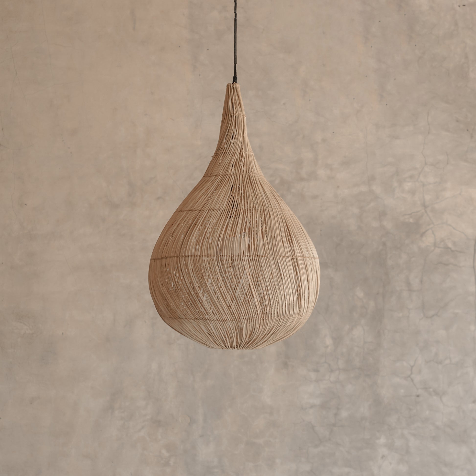 Woven pendant light against a textured beige wall