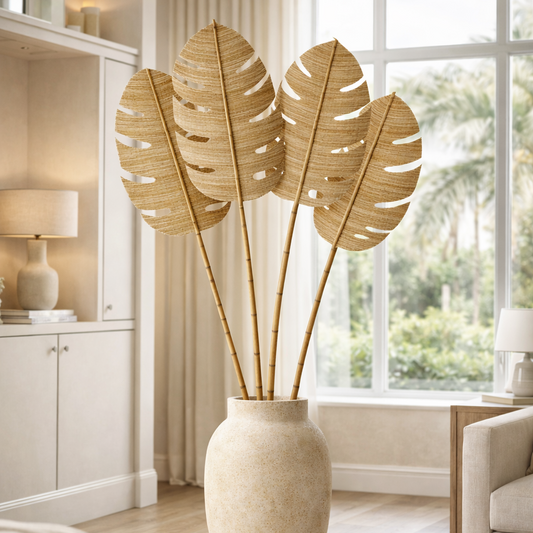 Decorative plant in a vase on a coffee table in a living room with large windows.