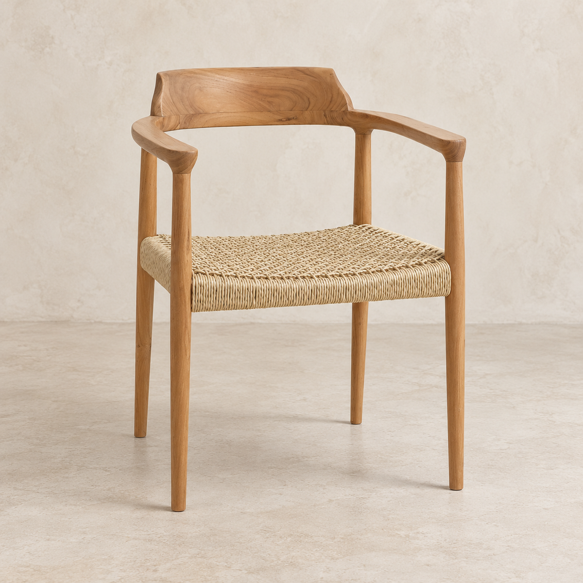 A mid-century modern wooden armchair with a natural oak frame and a woven jute seat, set against a textured beige wall and floor.