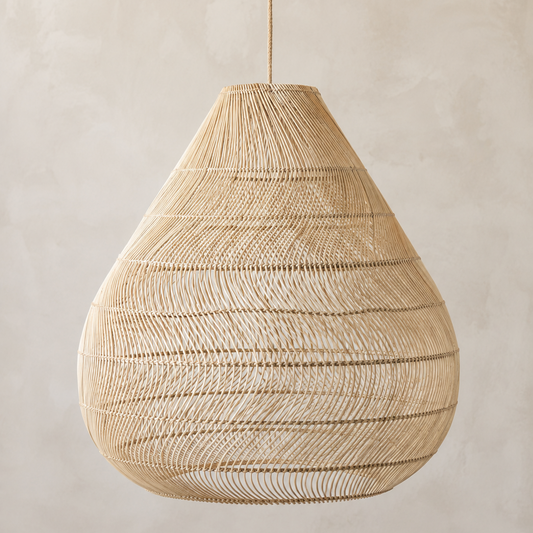 A teardrop-shaped woven pendant light made from natural beige raffia or wicker, suspended by a thin cord against a textured beige plaster wall.