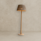 Wooden floor lamp with a textured shade on a neutral background