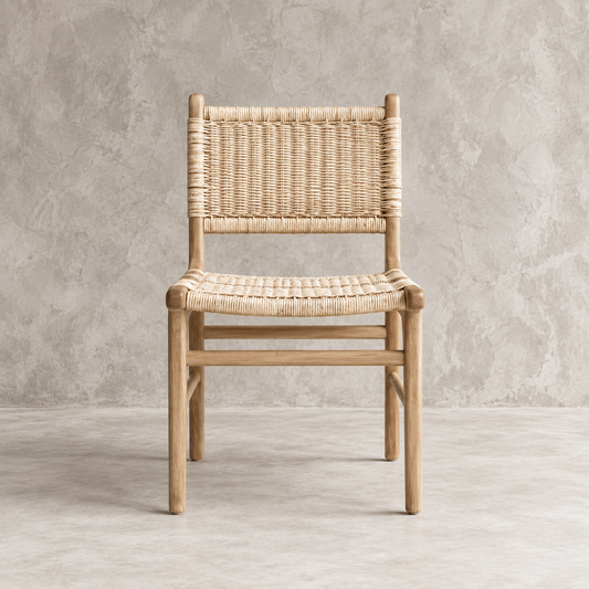 A light natural wood dining chair with a woven rattan or rope seat and back, shown against a textured concrete wall and floor.