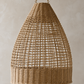 A teardrop-shaped woven rattan pendant light shade with a natural tan finish, suspended by a metal ring against a neutral textured beige wall.