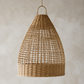 A natural woven rattan pendant light in a teardrop shape, hanging against a textured beige plaster wall.