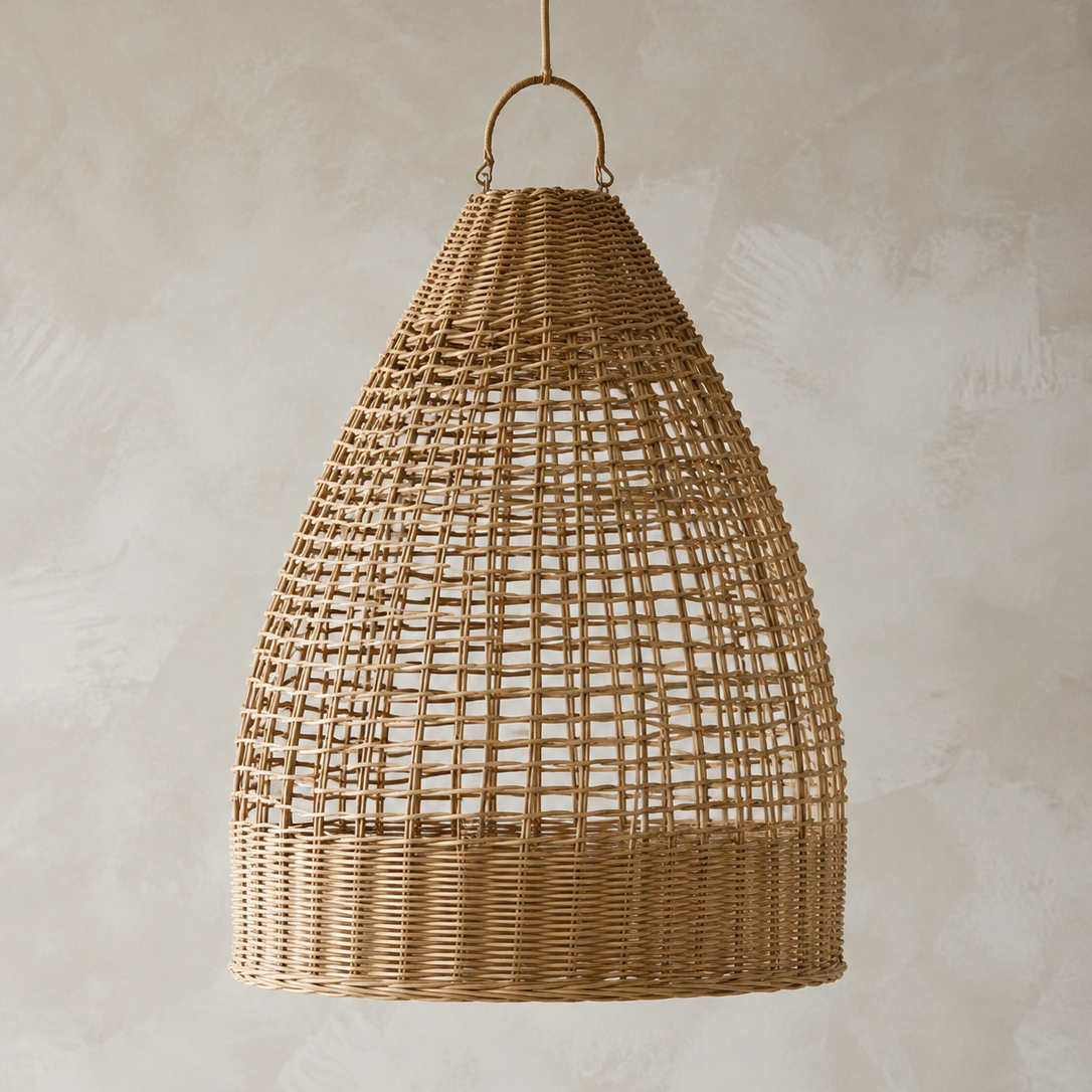 A natural woven rattan pendant light in a teardrop shape, hanging against a textured beige plaster wall.