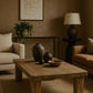Cozy living room with wooden coffee table, armchairs, and decorative items.