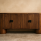 Wooden sideboard with a minimalist design against a beige wall.