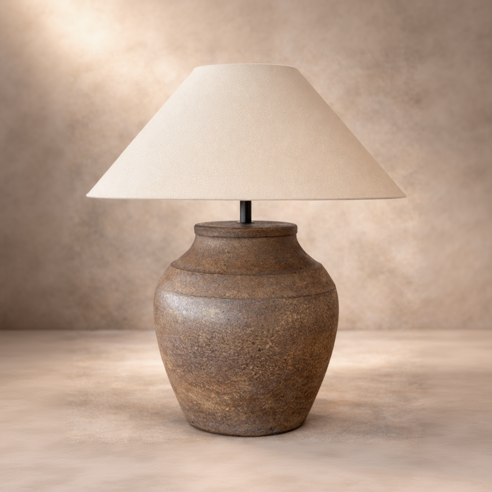Table lamp with a textured brown base and beige lampshade on a neutral background