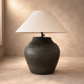 Table lamp with a dark brown base and white shade on a wooden surface.