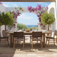 Outdoor dining area with a table and chairs under an archway decorated with flowers, overlooking a scenic view.