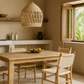Dining area with wooden table and chairs, wicker pendant light, and a window with natural light.
