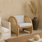 Wicker chair with white cushion in a room with beige walls and a wooden coffee table.