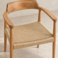 A modern wooden armchair with a curved natural oak frame and a woven natural fiber seat, shown on a light concrete floor against a neutral wall.