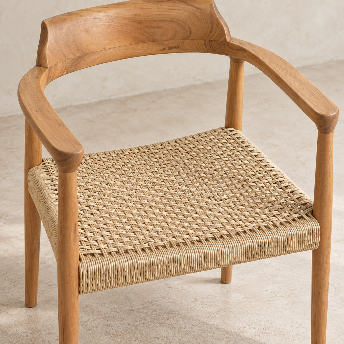 A modern wooden armchair with a curved natural oak frame and a woven natural fiber seat, shown on a light concrete floor against a neutral wall.